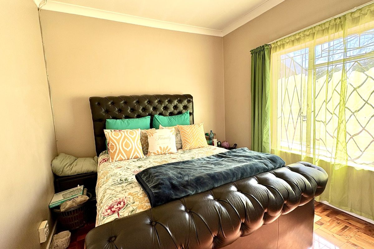 A bedroom featuring parquet flooring, coving, and a window fitted with a security gate.