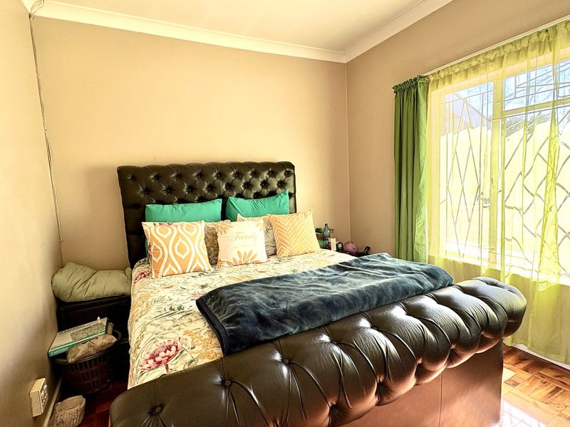 A bedroom featuring parquet flooring, coving, and a window fitted with a security gate.