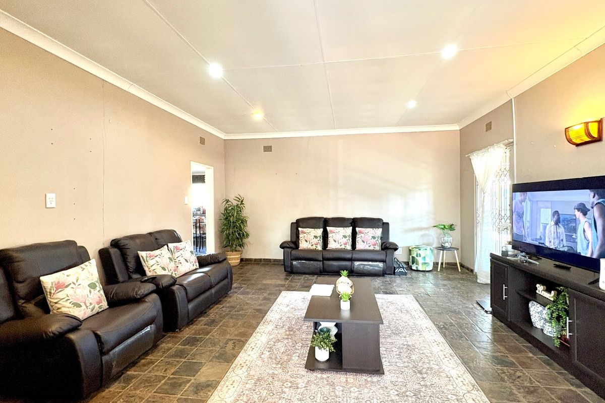 Spacious living room featuring dark tiled flooring, recessed downlighting, and neutral wall finishes, providing a comfortable and functional family entertainment area.