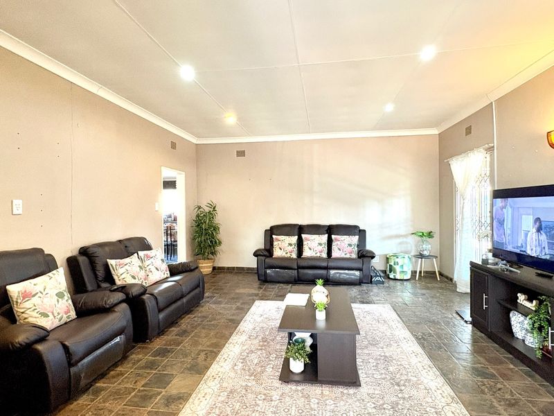 Spacious living room featuring dark tiled flooring, recessed downlighting, and neutral wall finishes, providing a comfortable and functional family entertainment area.
