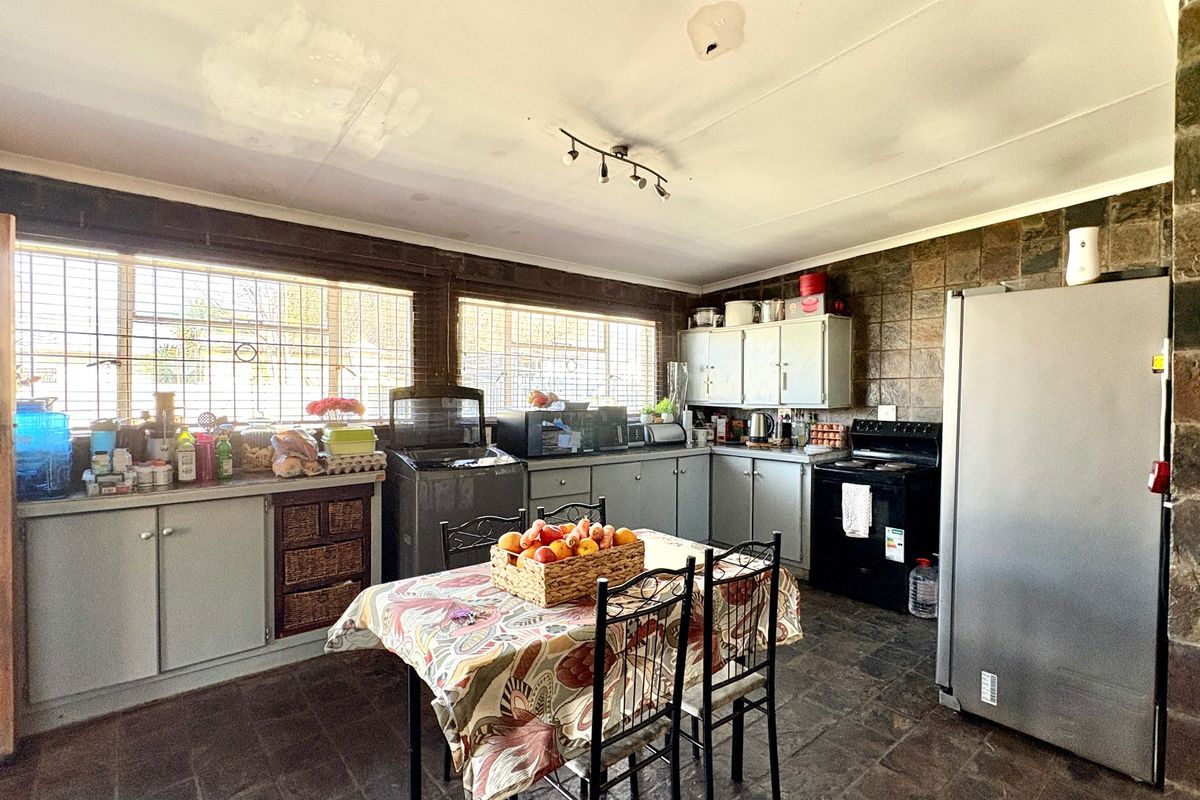 A dated kitchen featuring stone wall cladding, stone floor tiles, and built-in cabinetry, requiring cosmetic updates to modernize the space.