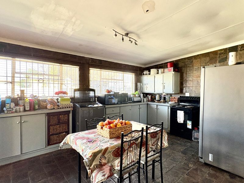 A dated kitchen featuring stone wall cladding, stone floor tiles, and built-in cabinetry, requiring cosmetic updates to modernize the space.