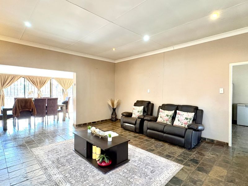 Spacious open-plan living area featuring tiled flooring, recessed lighting, and seamless flow to the adjacent dining space and patio.