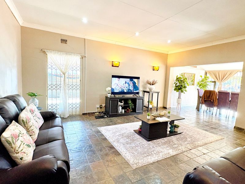 Spacious open-plan living area featuring tiled flooring, recessed lighting, and a seamless flow into the adjacent dining space.