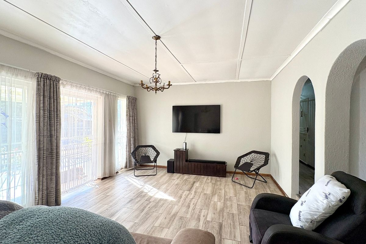 Spacious living room featuring wood-look tiled flooring, an arched entryway, and sliding glass doors leading to the exterior.