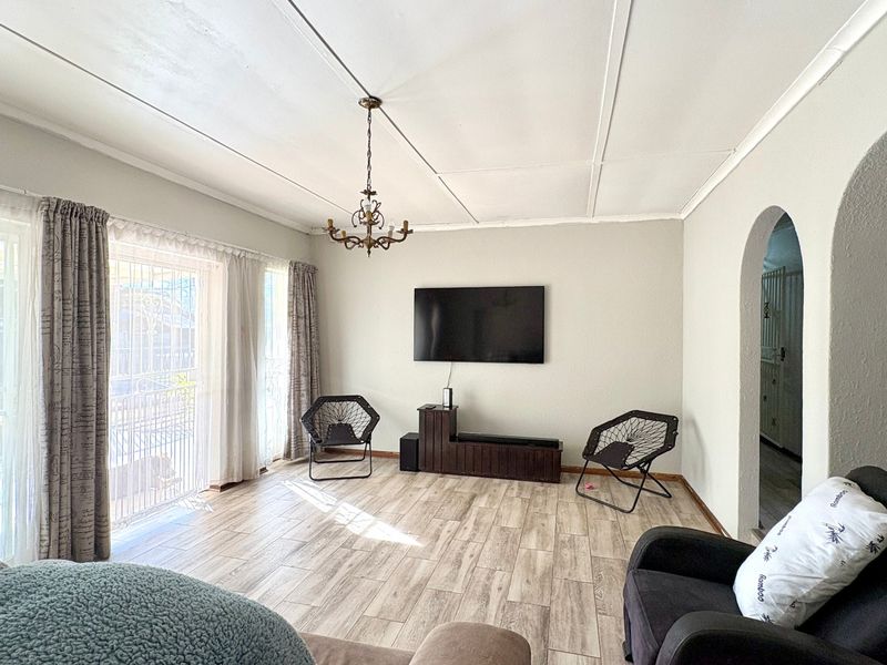 Spacious living room featuring wood-look tiled flooring, an arched entryway, and sliding glass doors leading to the exterior.