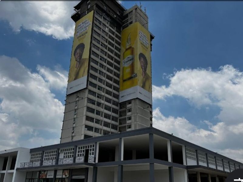 Exterior view of a high-rise apartment building featuring a prominent concrete structure and large commercial advertising billboards on the facade.