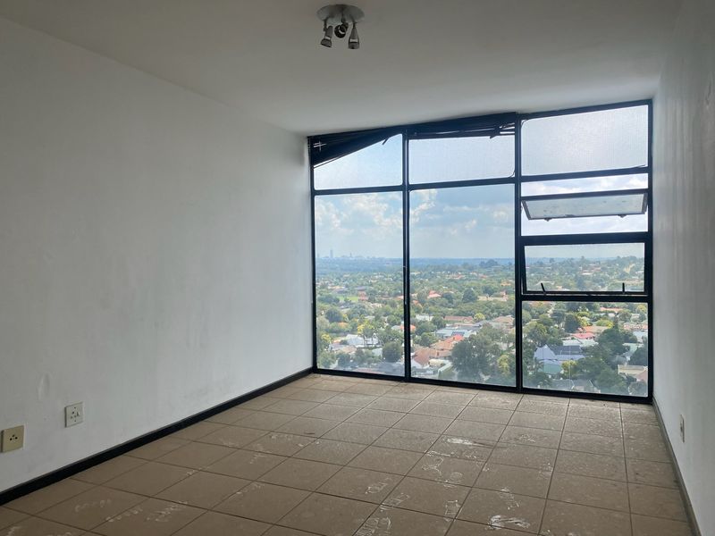 An empty bedroom featuring large floor-to-ceiling windows with expansive suburban views, tiled flooring, and a neutral interior finish.