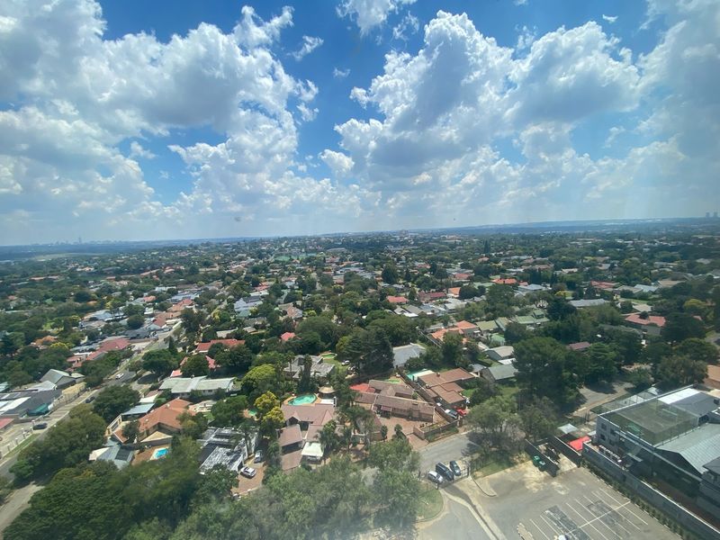 An elevated aerial view showcasing the surrounding residential neighborhood and urban landscape under a bright, cloudy sky.