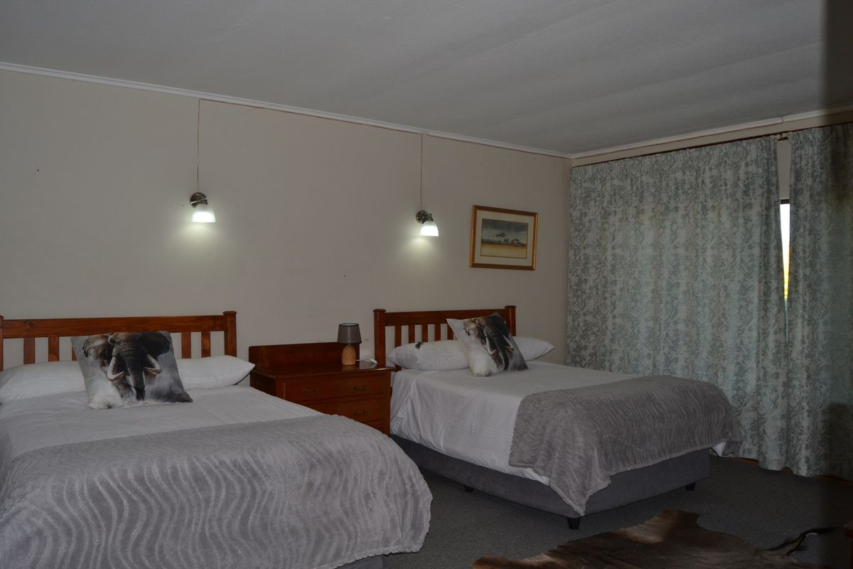 A functional bedroom featuring neutral wall finishes, wall-mounted lighting, and full-length window curtains.