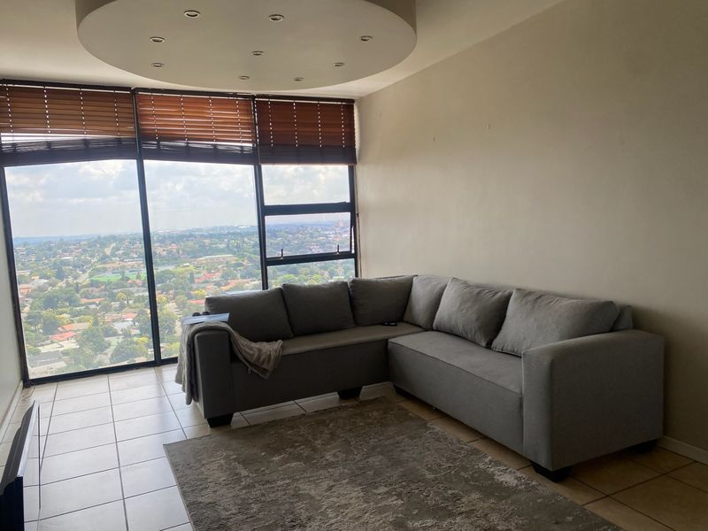 A living room featuring large floor-to-ceiling windows with expansive city views, tiled flooring, and recessed ceiling lighting.