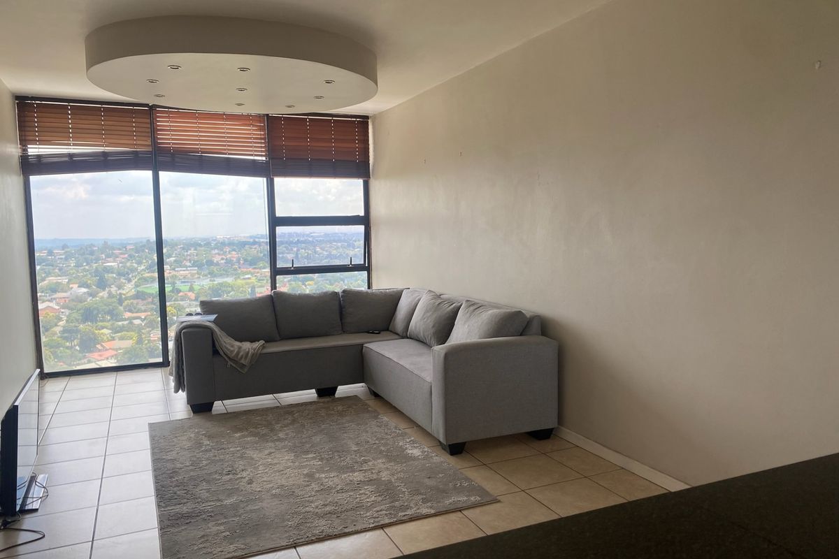 A bright living room featuring large floor-to-ceiling windows with expansive views, tiled flooring, and a unique circular recessed ceiling detail.