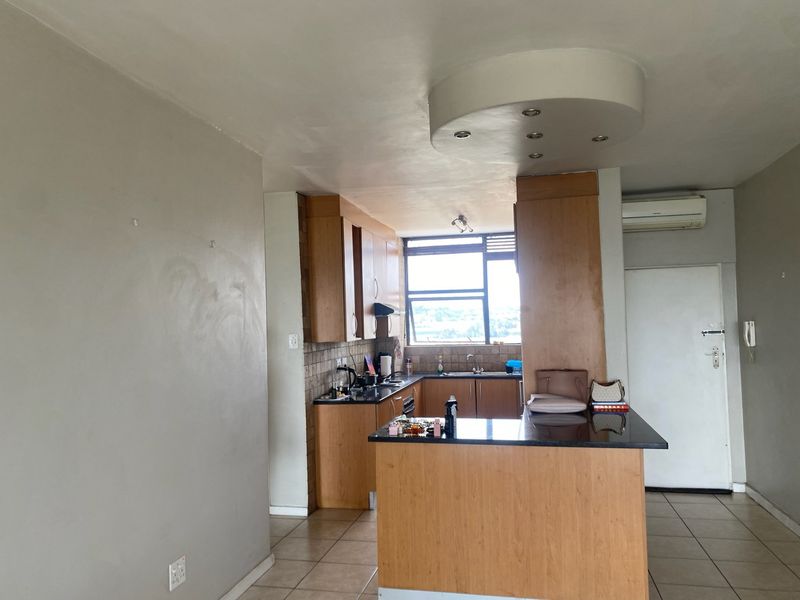Open plan kitchen featuring wooden cabinetry, granite countertops, and tiled flooring, integrated with a living area and air conditioning unit.