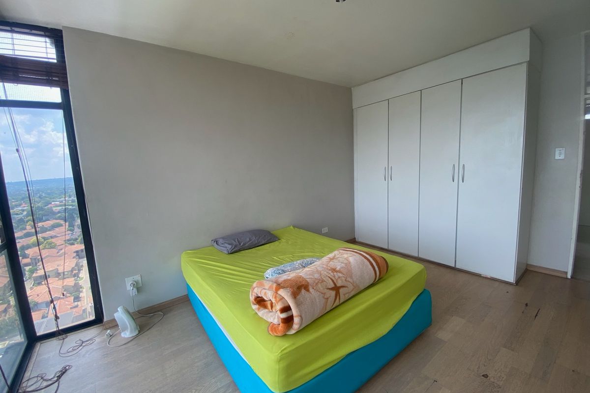 Bedroom featuring laminate flooring, a large built-in wardrobe, and a floor-to-ceiling window offering expansive views.
