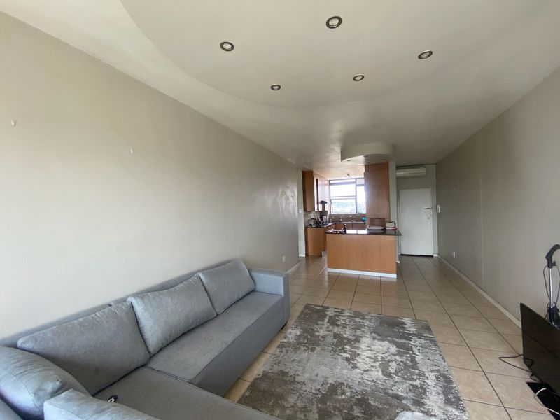 Open-plan living area featuring tiled floors, recessed ceiling lights, and a functional kitchen with cabinetry and an island.