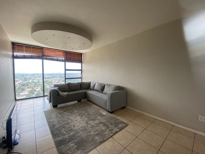 A living room featuring large floor-to-ceiling windows with expansive views, tiled flooring, and a unique circular recessed ceiling light fixture.