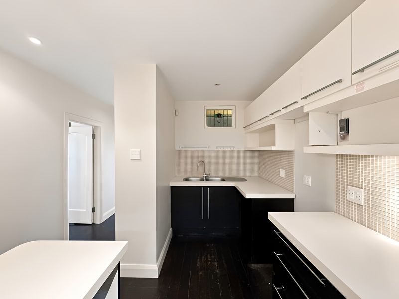 A clean, functional kitchen featuring dark cabinetry, white countertops, and a mosaic tile backsplash, offering a neutral canvas for potential updates.