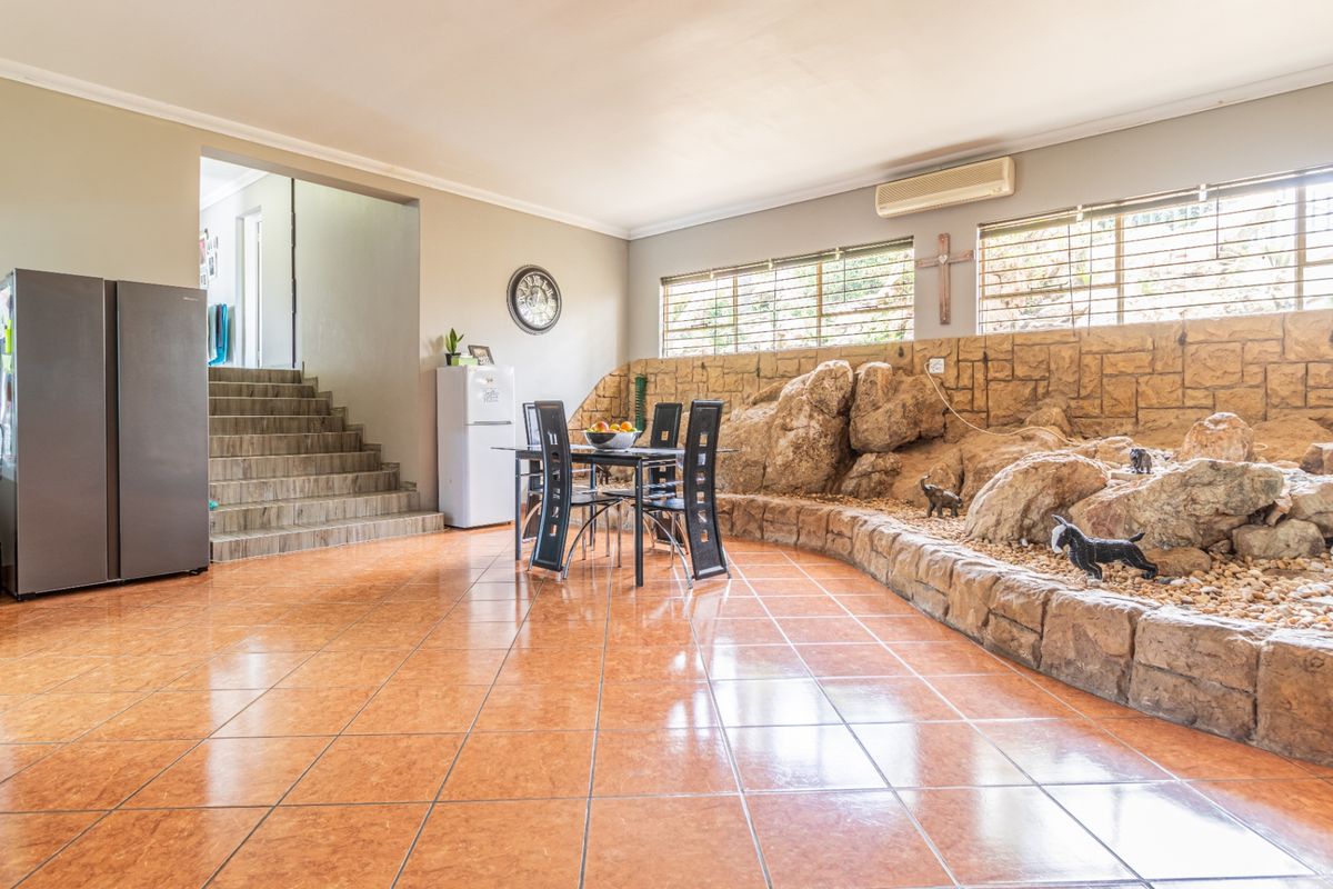 Spacious living area featuring unique built-in rock feature wall, tiled flooring, and a staircase leading to an upper level.