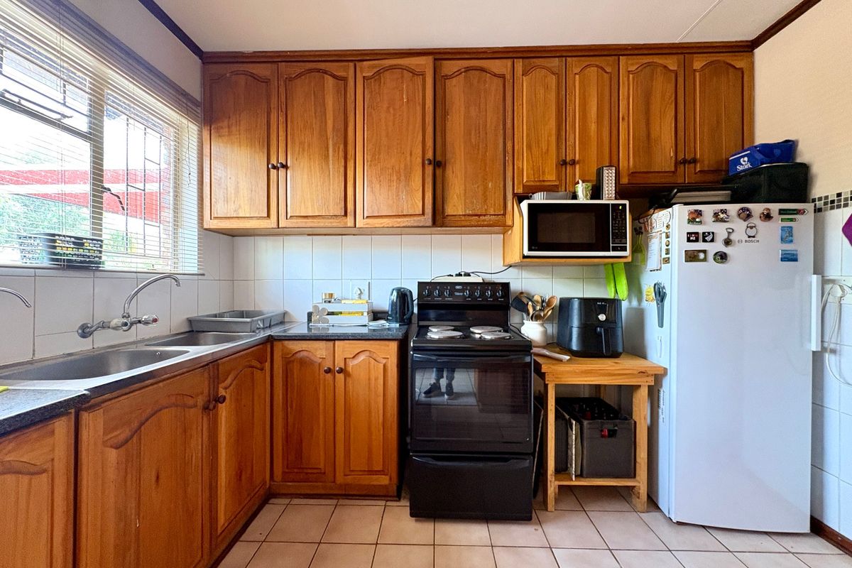 A functional kitchen featuring traditional wooden cabinetry, tiled backsplash, double basin sink, and built-in oven and hob.