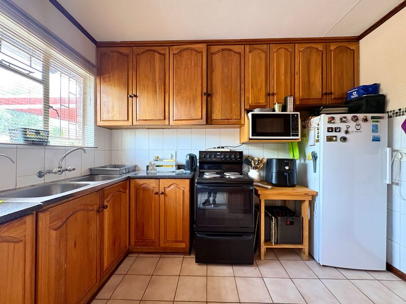 A functional kitchen featuring traditional wooden cabinetry, tiled backsplash, double basin sink, and built-in oven and hob.