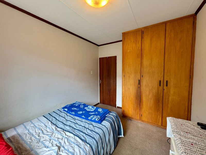 A bedroom featuring built-in wooden wardrobes, carpeted flooring, and a standard ceiling light fixture.