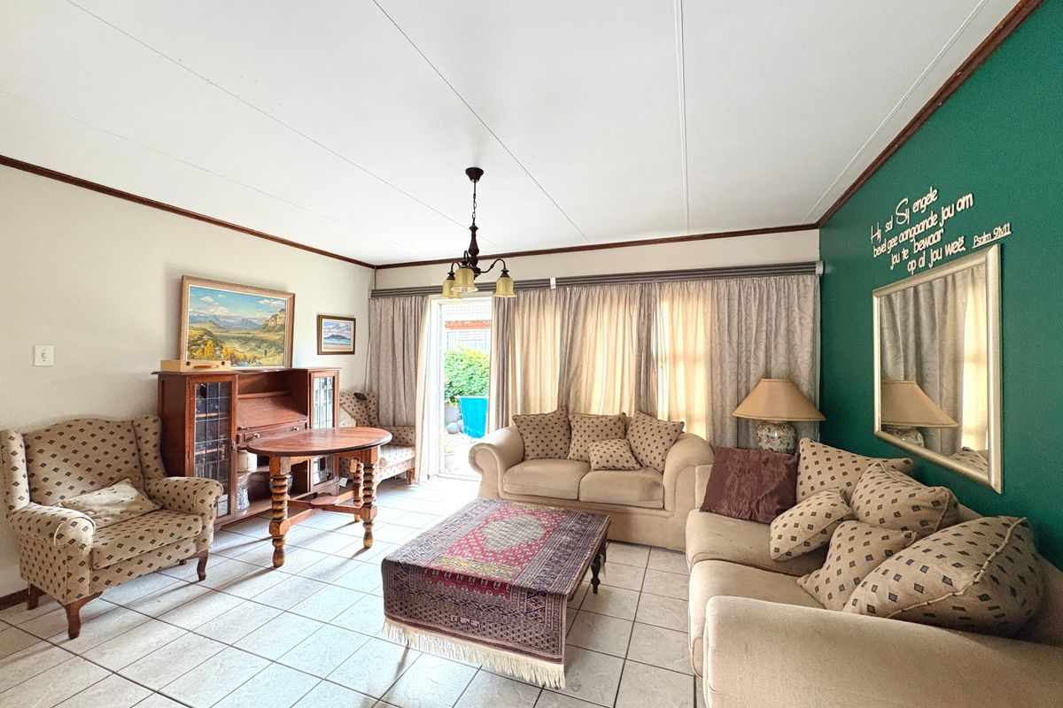 A spacious living room featuring tiled flooring and a sliding glass door providing access to the outdoor area.