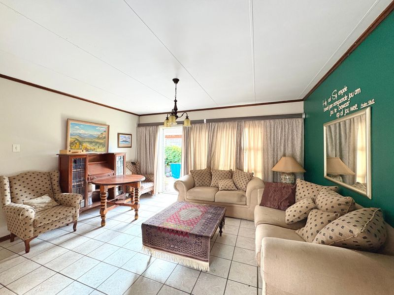 A spacious living room featuring tiled flooring and a sliding glass door providing access to the outdoor area.