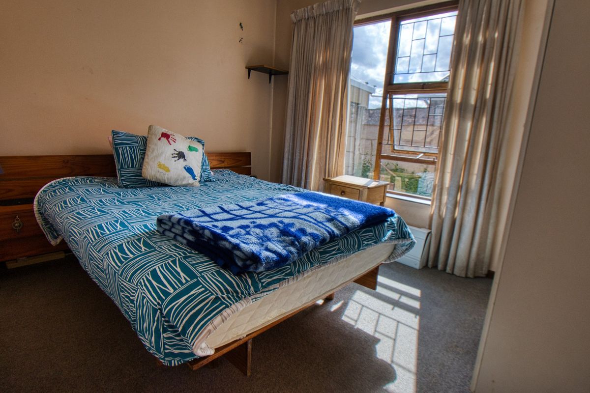 A bedroom featuring carpeted flooring and a window with security bars, requiring cosmetic updates to improve the overall condition and appeal.