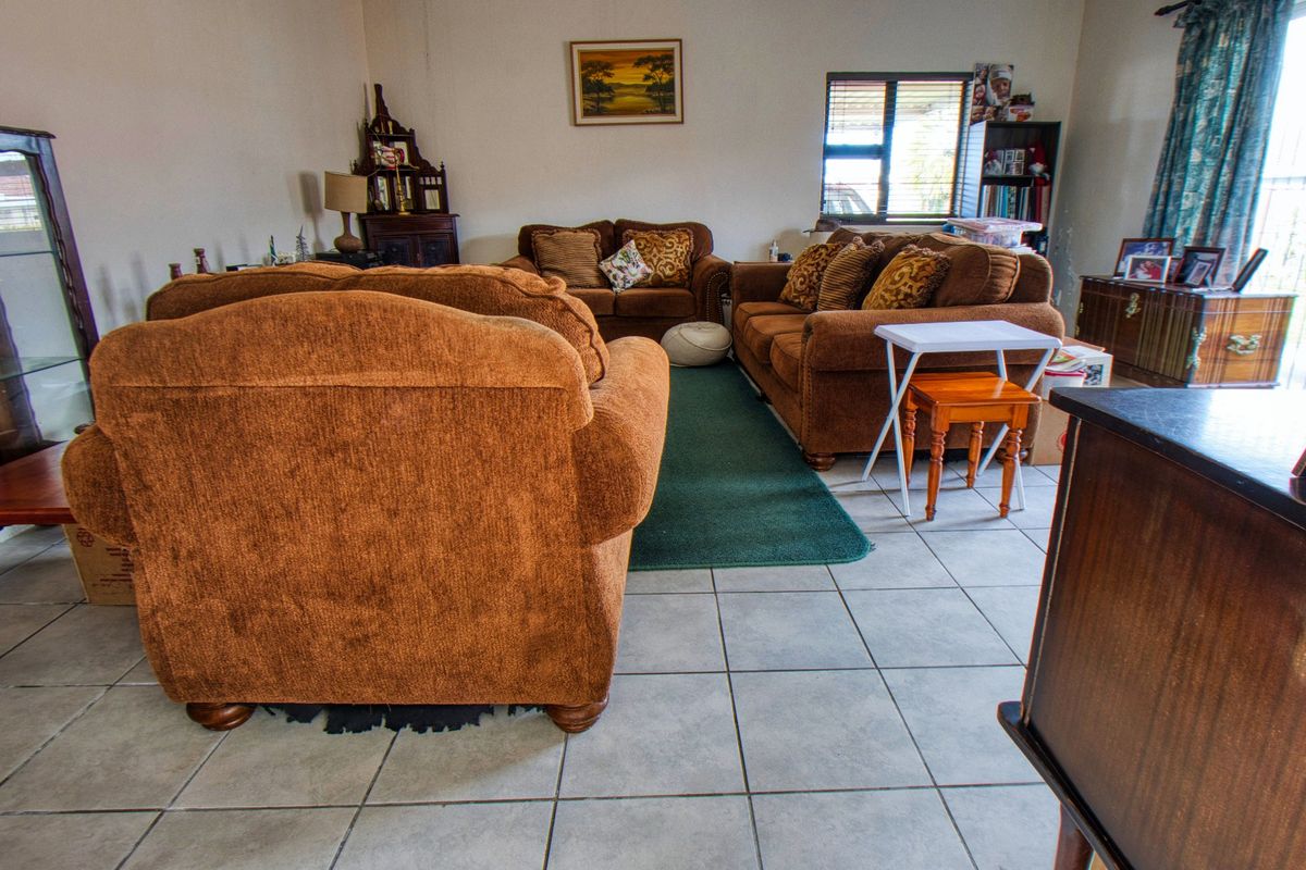 A spacious living room featuring neutral tiled flooring and natural light from a side window, offering a comfortable and functional layout.