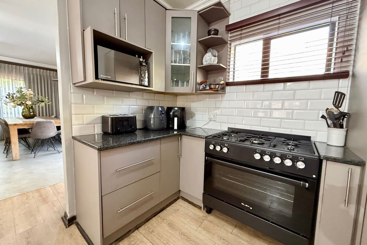 Modern kitchen featuring grey cabinetry, granite countertops, subway tile backsplash, and a professional-style gas stove with oven.