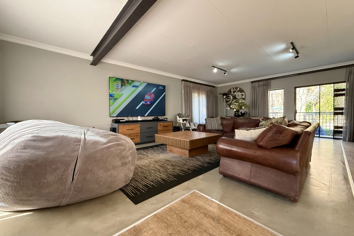 Spacious living room featuring polished concrete floors, an exposed steel beam ceiling detail, and large sliding glass doors providing natural light.