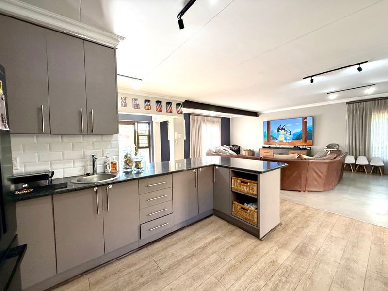 Spacious open-plan living area featuring a modern kitchen with grey cabinetry, granite countertops, subway tile backsplash, and seamless flow into the lounge.