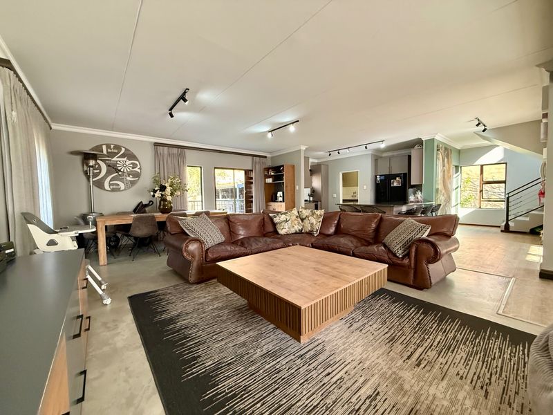 Spacious open-plan living area featuring polished concrete floors, modern track lighting, and a seamless transition to the kitchen and staircase.