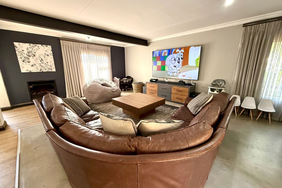 Spacious living room featuring a built-in fireplace, exposed ceiling beam, and polished concrete flooring, creating a comfortable and modern family area.