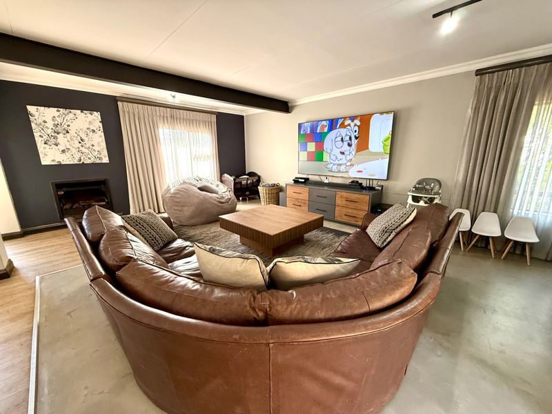 Spacious living room featuring a built-in fireplace, exposed ceiling beam, and polished concrete flooring, creating a comfortable and modern family area.