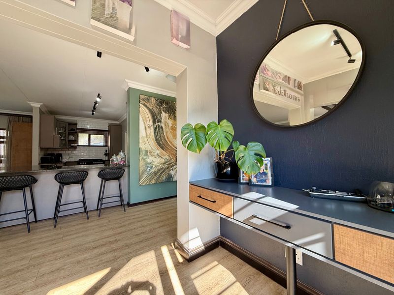 An open-plan living area featuring laminate flooring, a modern kitchen with a breakfast bar, and stylish accent walls with recessed lighting.