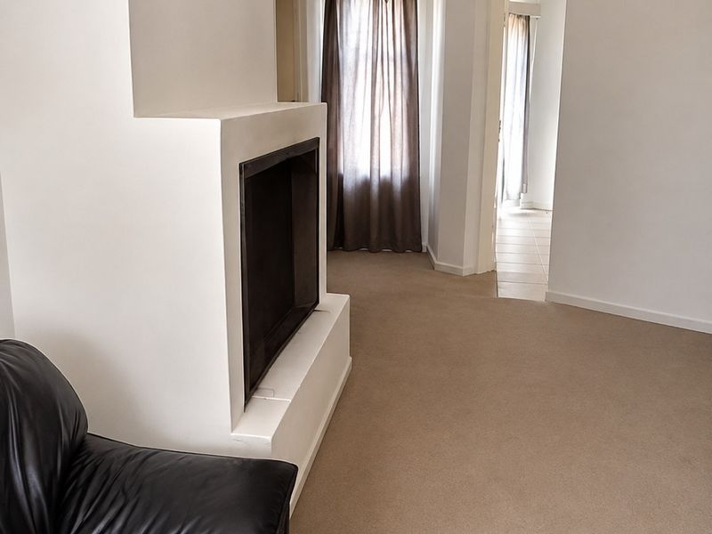 A living room featuring a built-in fireplace and neutral carpeted flooring, leading through to an adjacent room.