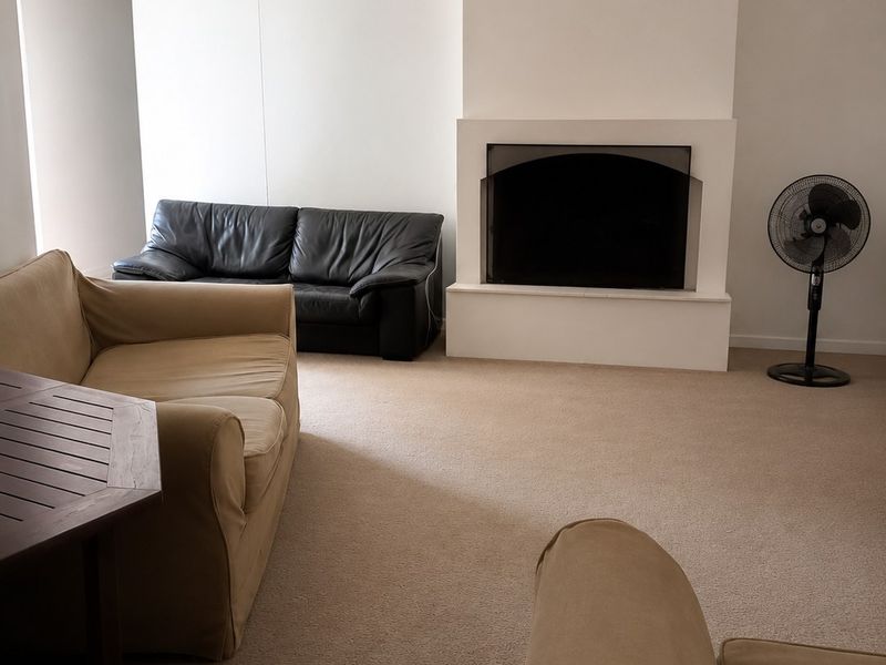 A living room featuring a central built-in fireplace and neutral carpeting, offering a blank canvas for interior design updates.