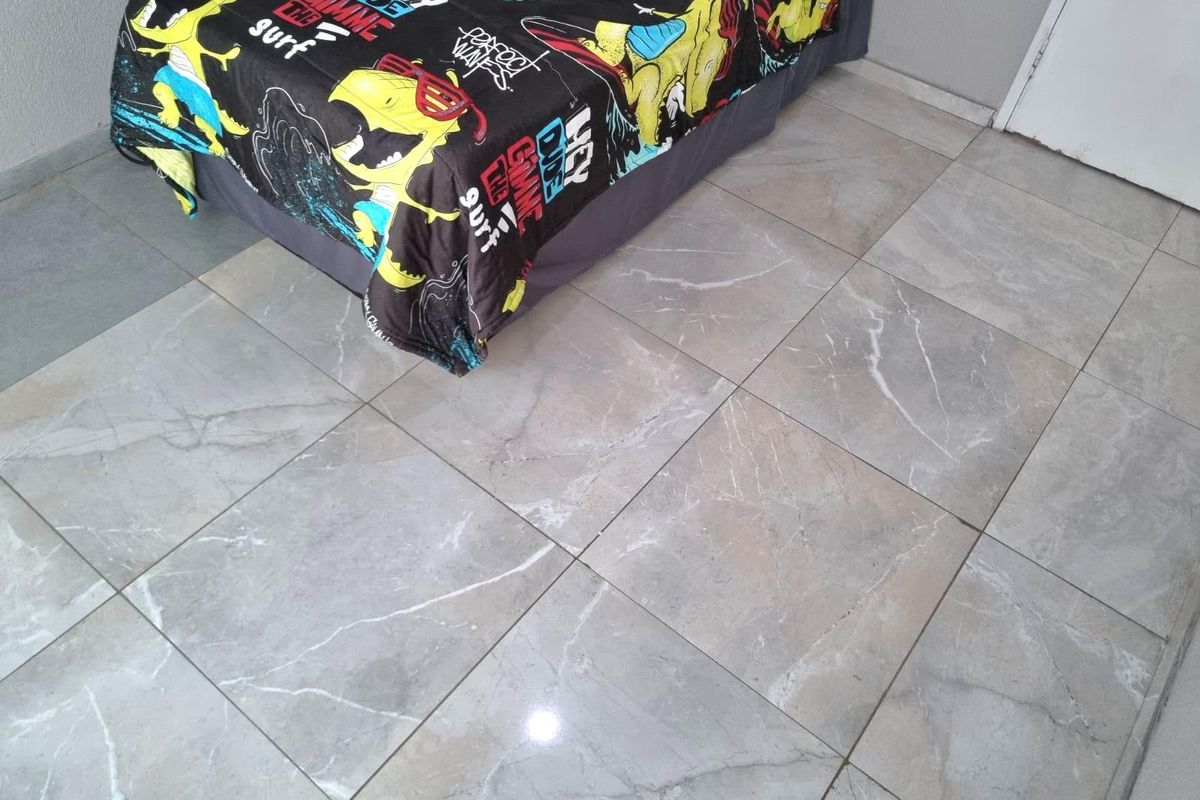 A bedroom featuring modern, large-format marble-look porcelain floor tiles throughout the space.