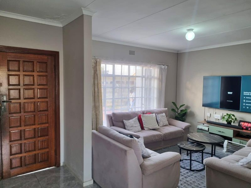 A comfortable living room featuring a timber panel door, large window for natural light, and visible ceiling detail.