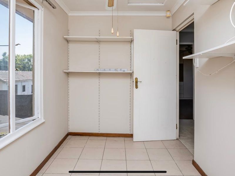 A functional utility space featuring tiled flooring, wall-mounted shelving, and a large window providing natural light.