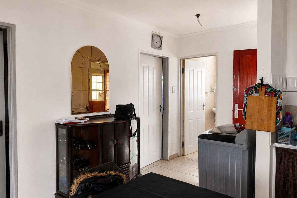 A functional kitchen area featuring tiled flooring and multiple internal access doors, with visible potential for cosmetic updates and improved lighting fixtures.