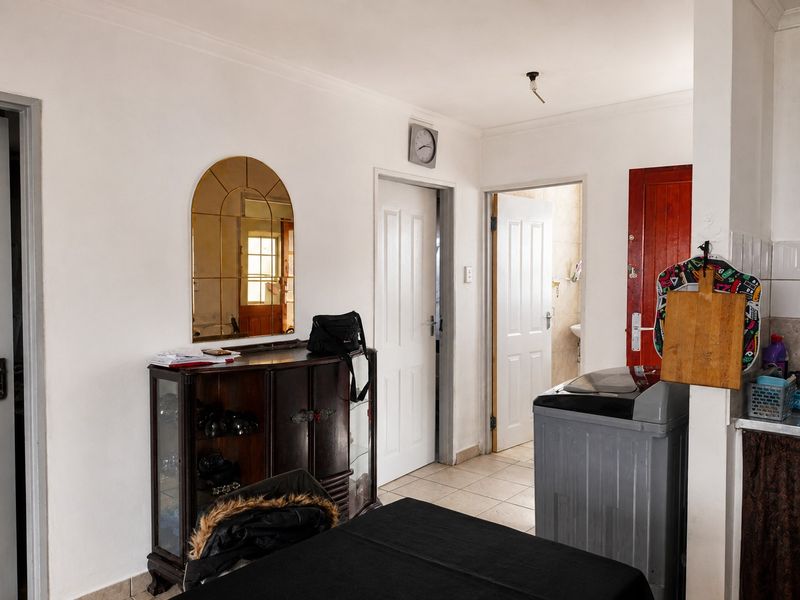 A functional kitchen area featuring tiled flooring and multiple internal access doors, with visible potential for cosmetic updates and improved lighting fixtures.