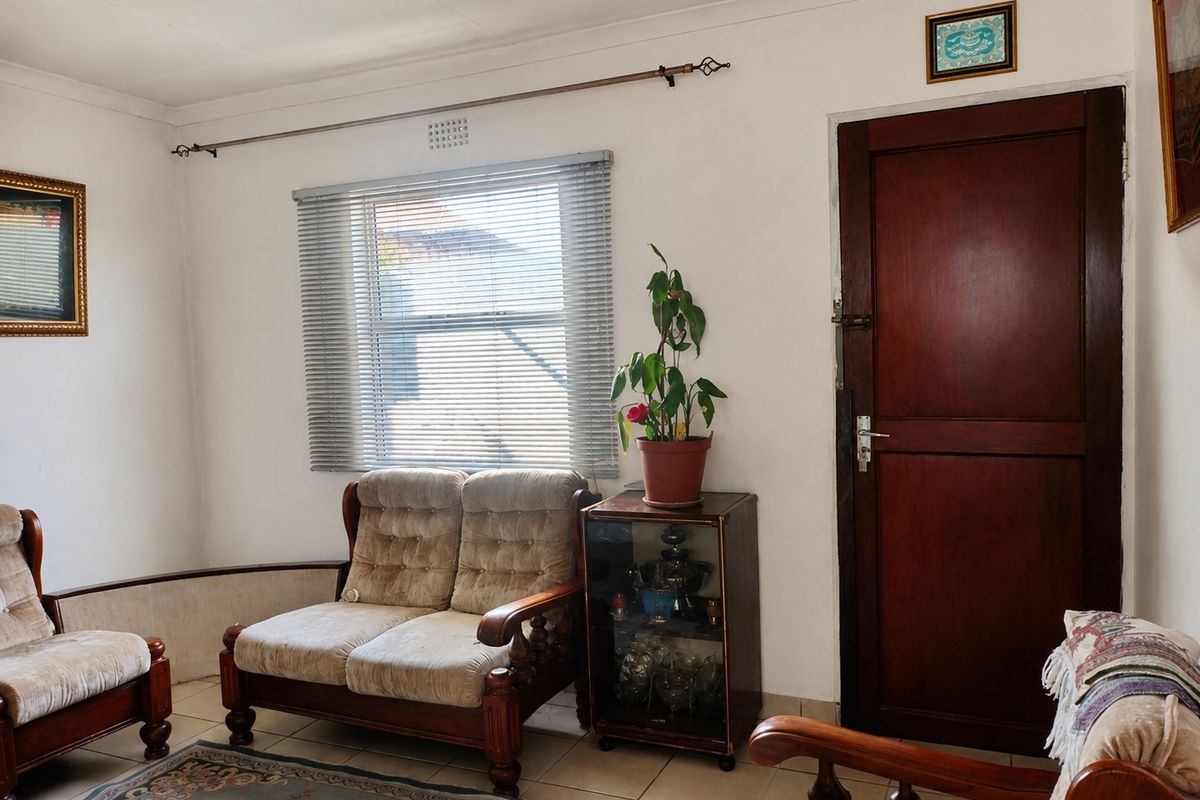 A living room featuring tiled flooring, a timber door, and a window fitted with venetian blinds.