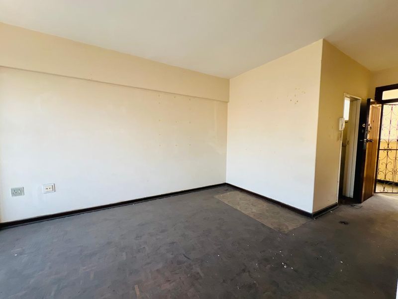 An empty living area featuring worn flooring and neutral walls, providing a blank canvas for renovation or interior design updates.