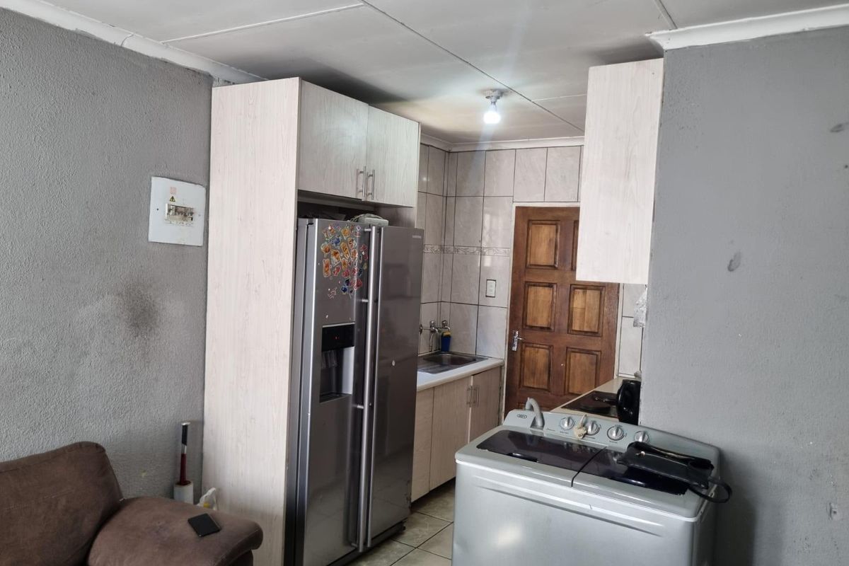 A compact kitchen area featuring built-in cabinetry, tiled splashbacks, and tiled flooring, requiring cosmetic updates to improve the overall aesthetic and finish.