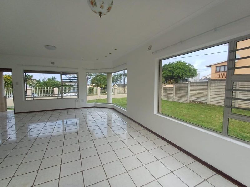 A bright, empty living room featuring large windows, tiled flooring, and neutral walls, offering a clean canvas for interior design.