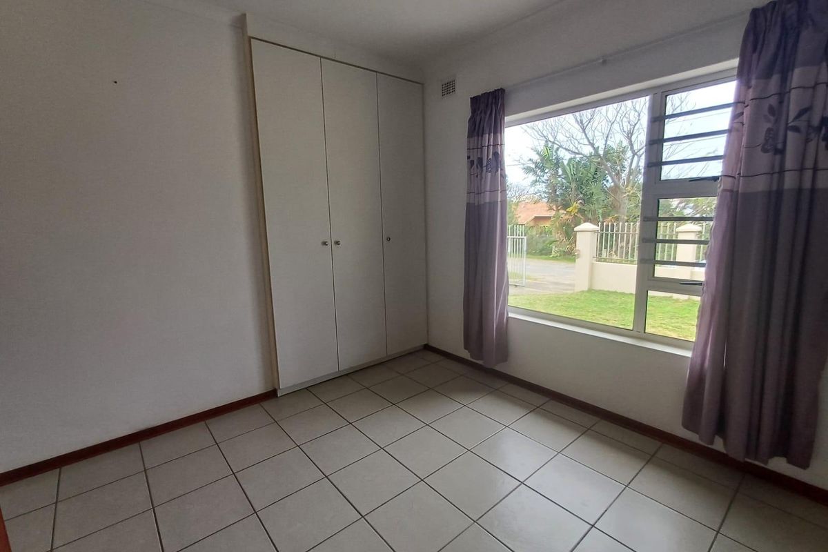 A bright, empty bedroom featuring neutral tiled flooring and built-in cupboards, offering a clean and versatile space ready for personalization.