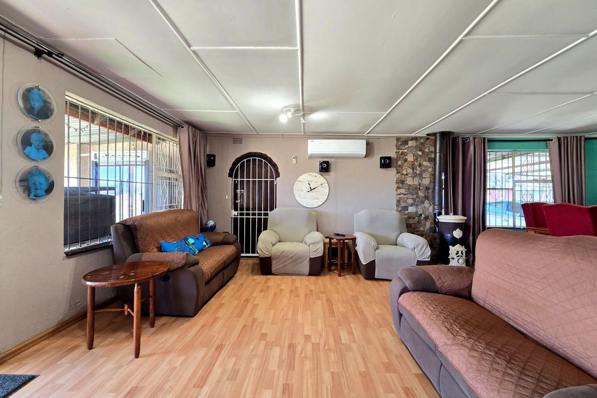 Spacious living room featuring a stone accent wall, wood-burning stove, split-system air conditioning, and laminate flooring with security features on windows and doors.