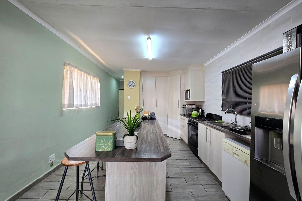 A functional kitchen featuring a central island, laminate countertops, built-in cabinetry, and tiled flooring, offering a practical layout for cooking and dining.